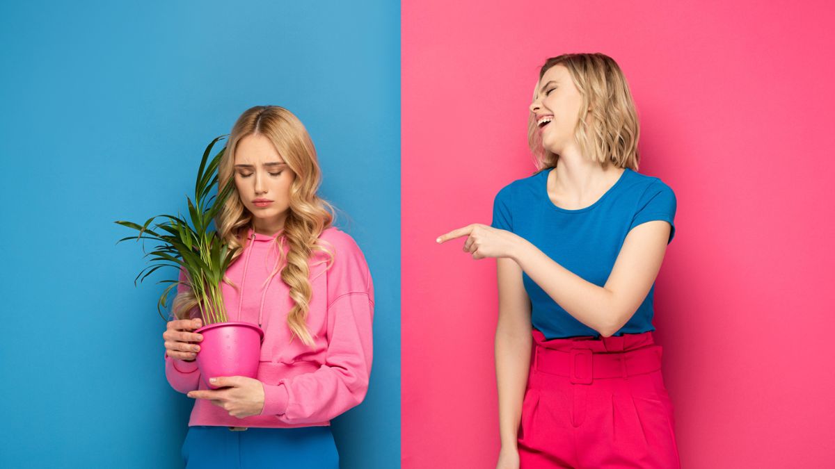 One Sister pointing and laughing at another holding a plant looking sad