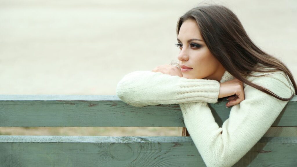 pensive woman leaning on a bench thinking