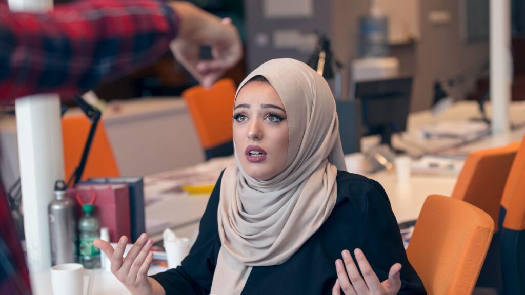 Racist muslim woman being pointed at and looking upset.