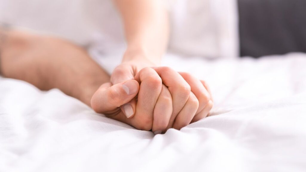 Sex a woman and mans hands clasped together in bed
