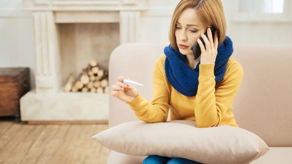 Sick Voice woman talking on the phone looking at thermometer looking sick