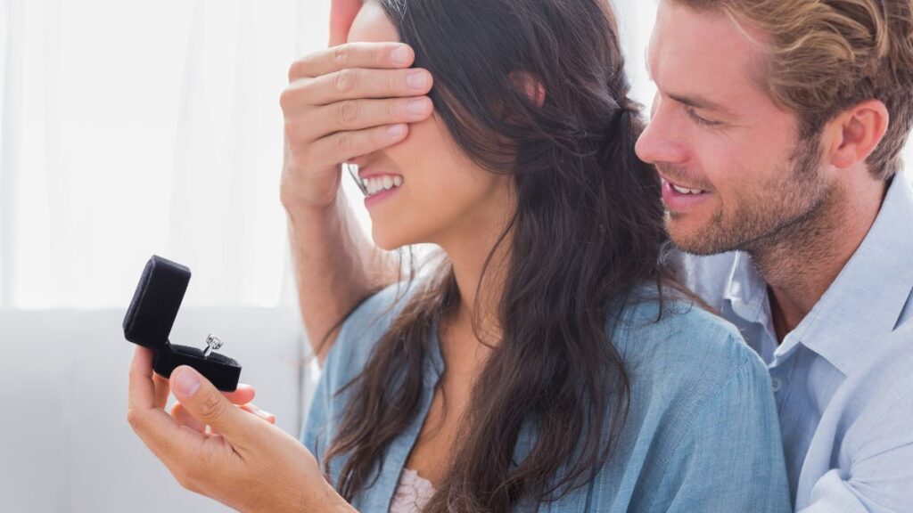 Man covering a womans face with hand hiding engagement ring