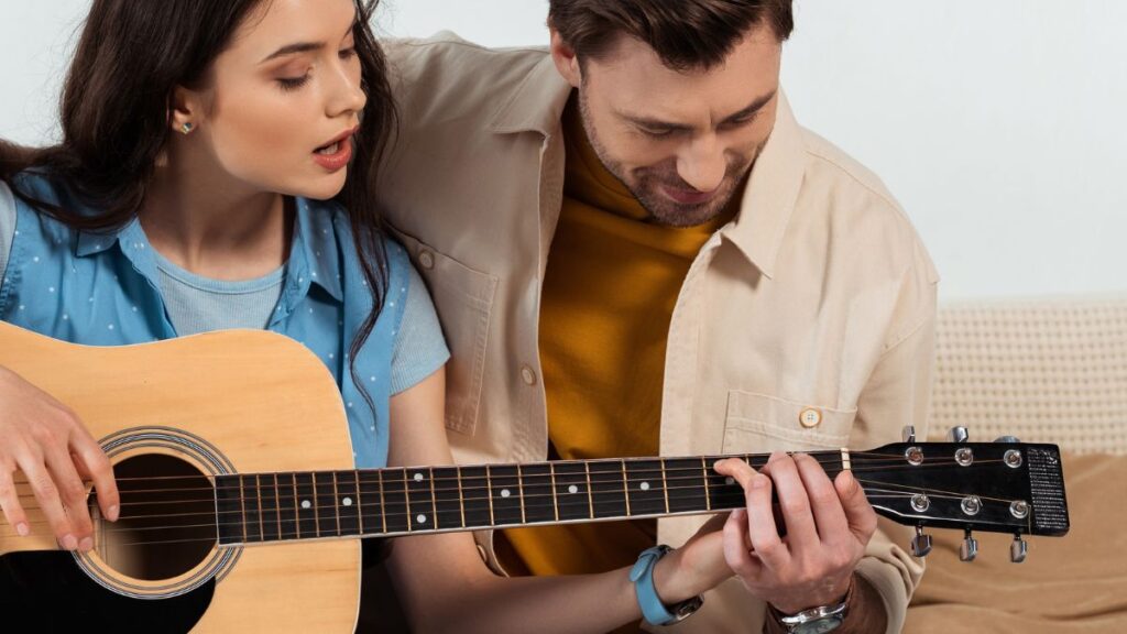 Teaching man teaching woman to play guitar