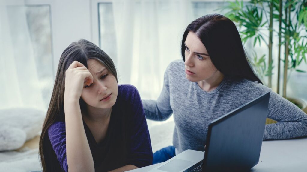 The Victim woman and daughter upset talking at the computer.