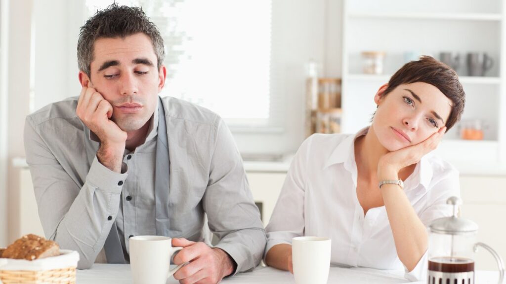 unhappy couple sitting at a table with coffee