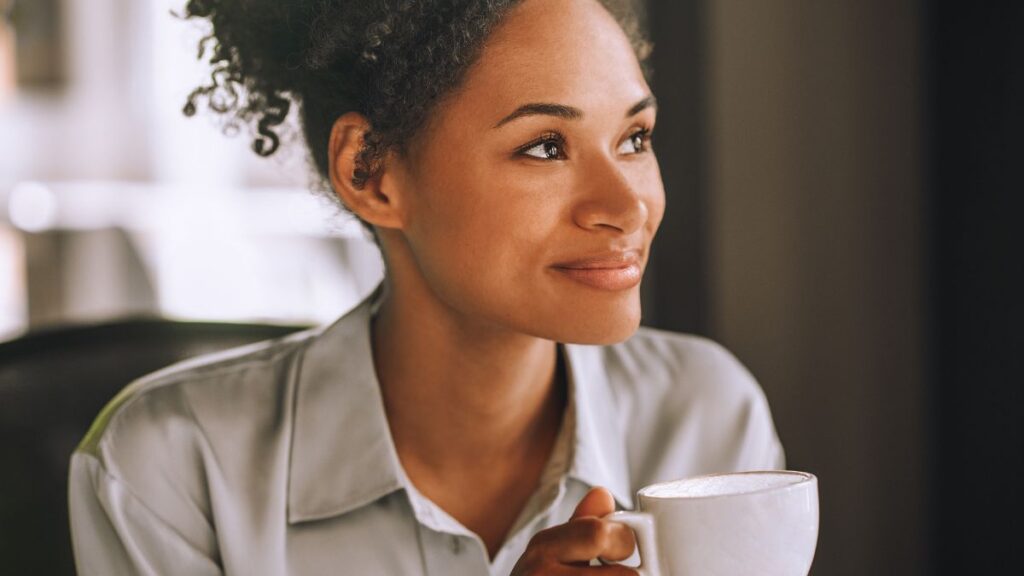 Validate Feelings: woman sitting and smiling with a coffee cup