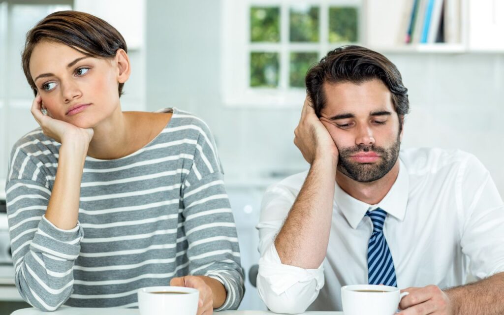 woman and man looking sad and bored with coffee