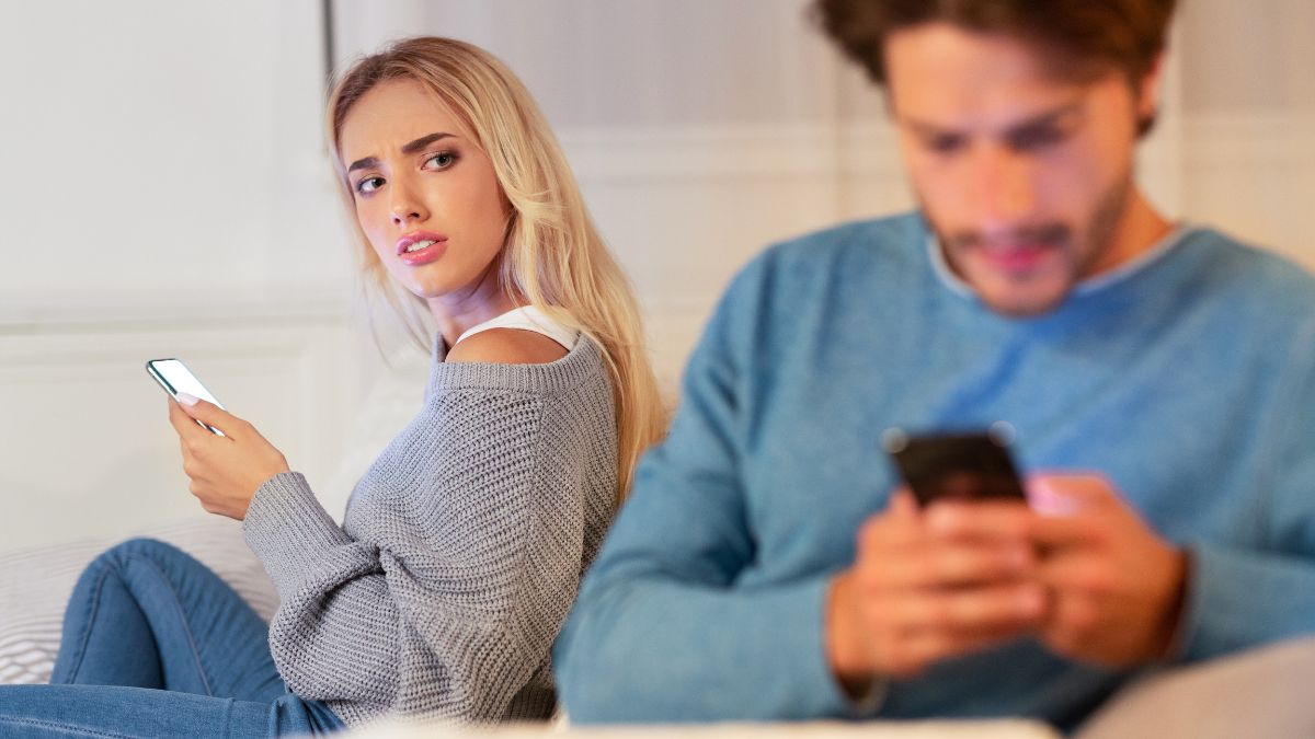 Woman and man on their phones, woman looking at the man suspiciously