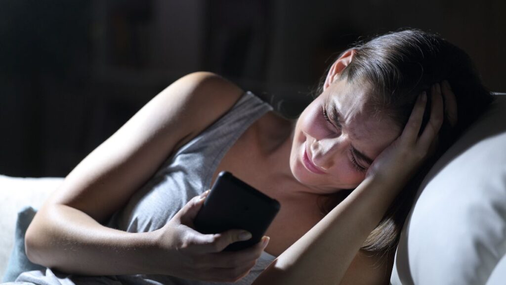 woman crying on bed with phone