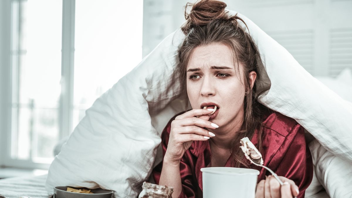 woman dealing with a break up, in bed drinking wine and eating junk food