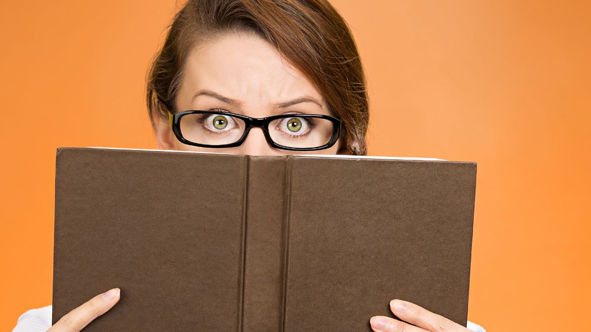 Woman hiding behind a book. You only see her eyes