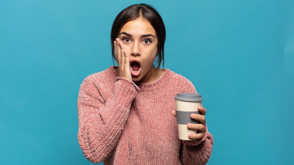woman holding a coffee cup and looking shocked