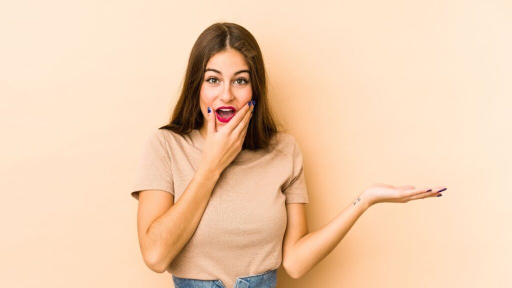 Woman holding her cheeks with one hand questioning with her other hand out