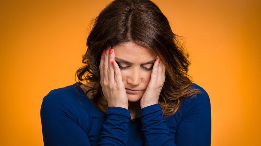 woman holding her face looking stressed