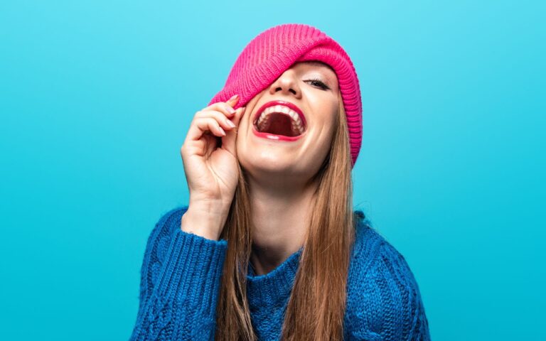 woman laughing with her had over one eye
