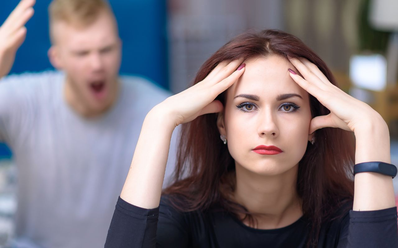 woman looking annoyed as a man yells behind her