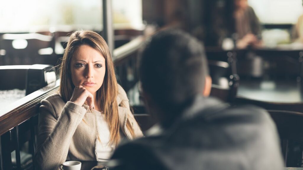 Woman looking at a man with a questioning look on her face. Picture taken from behind the man