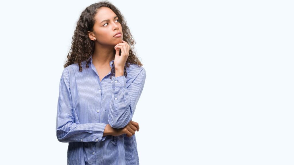 woman looking away and thinking with her arms crossed and hand on her chin