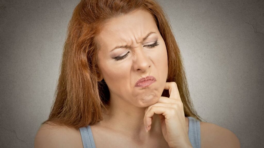 woman looking irritated with her hand on her face