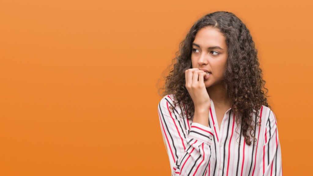 woman looking nervous biting nails and looking away