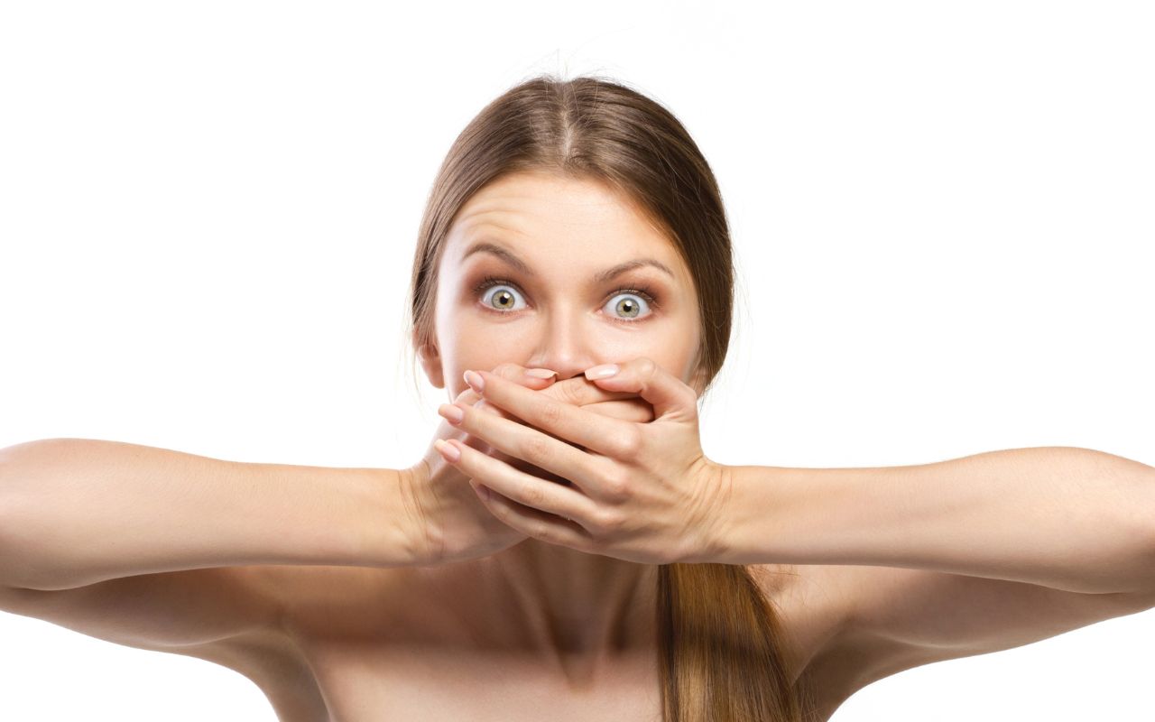 woman looking shocked but covering her mouth