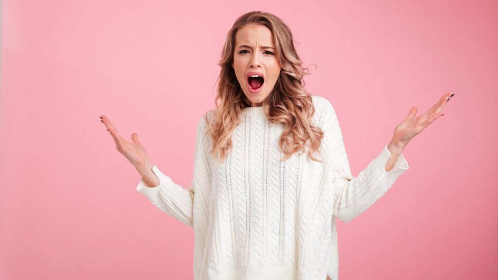 woman looking surprised and upset with mouth open and hands up