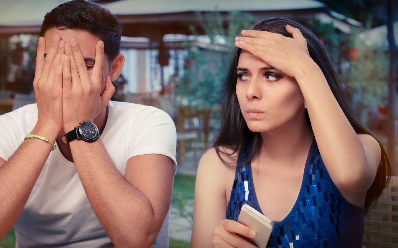 woman looking unhappy at a man - man covering his face