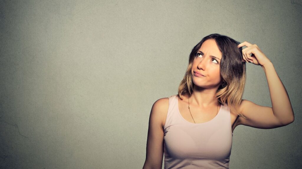 woman looking up and thinking while scratching her head