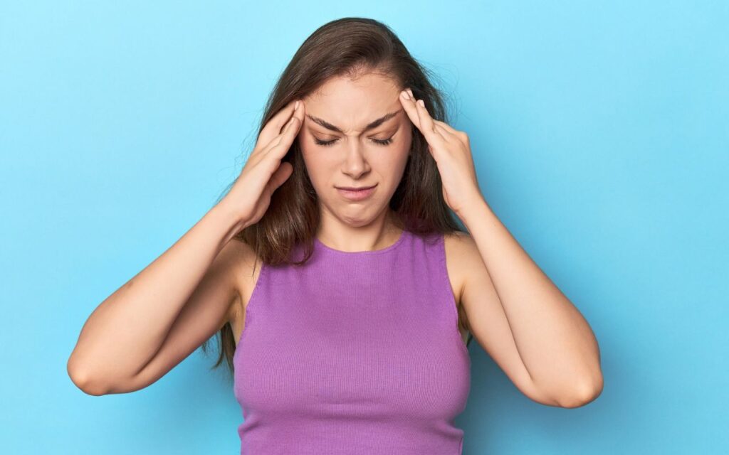 woman looking upset holding her head looking down with eyes closed