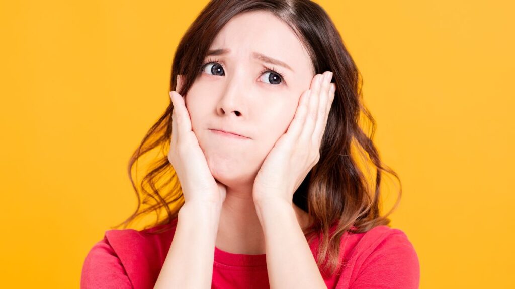 woman looking upset with her hands on her face