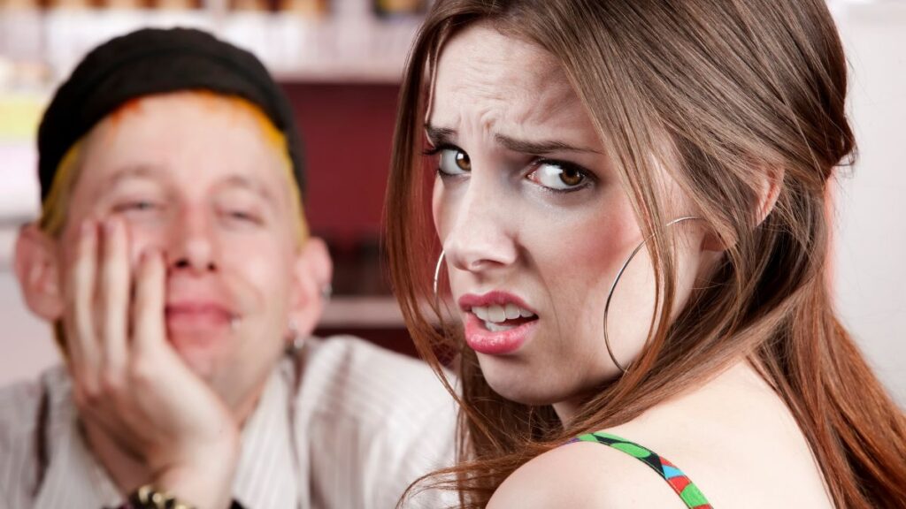 woman sitting at a table making a disgusted face across from a man