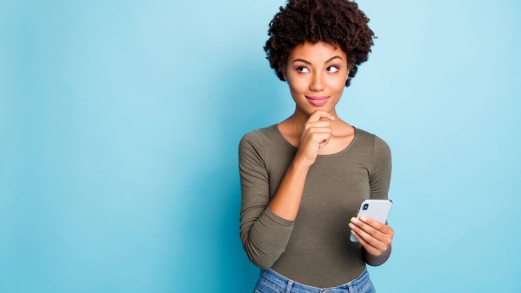 woman thinking with hand on her chin and holding her phone