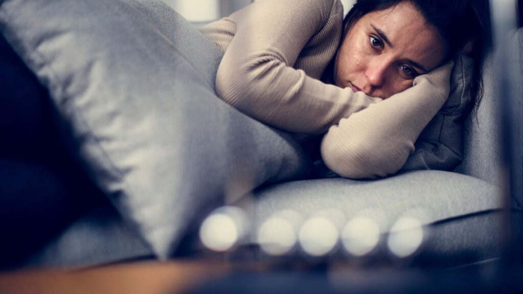 woman upset and depressed laying on the couch