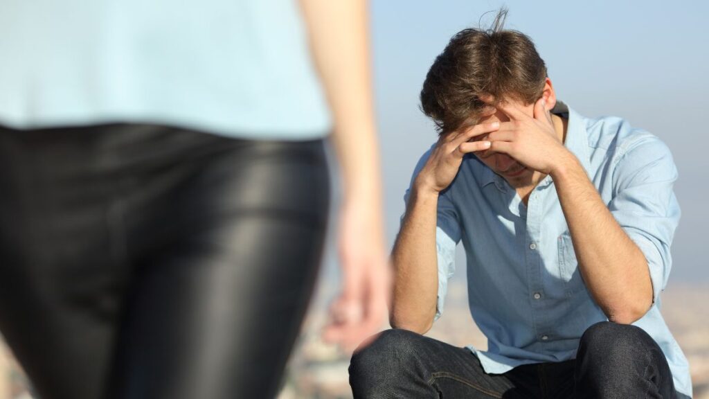 woman walking away and man sitting upset outside