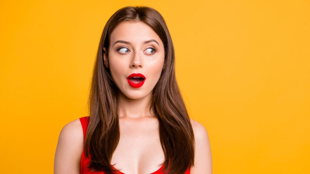 Woman wearing red lipstick looking to the side surprised