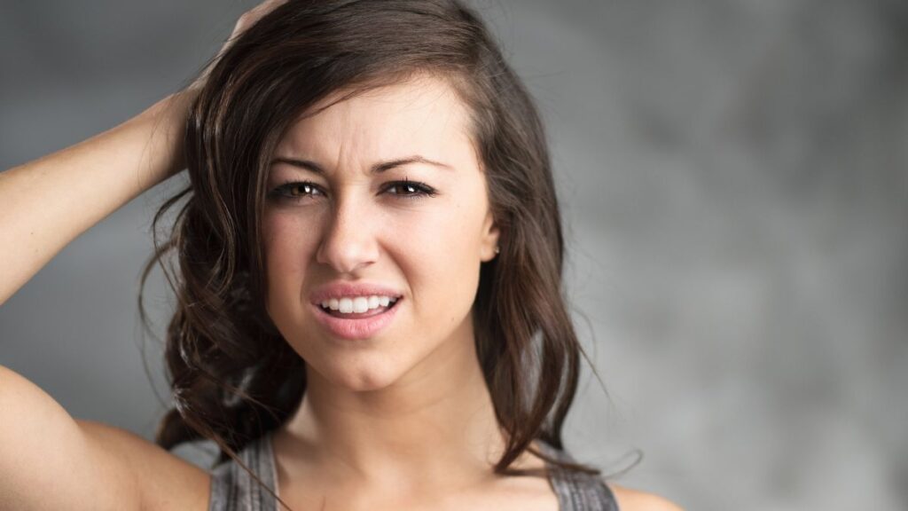 woman with her hand on her head looking confused