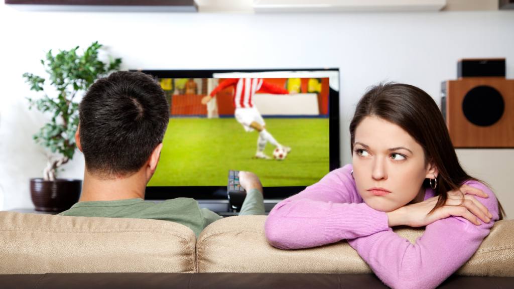 annoyed woman while man watches football