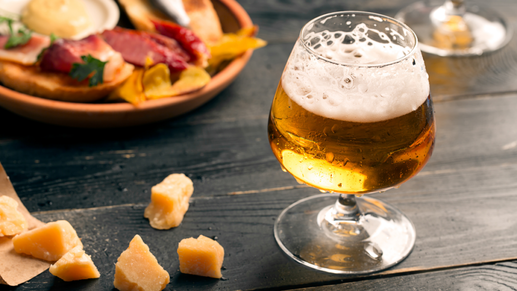 beer in a glass next to charcuterie