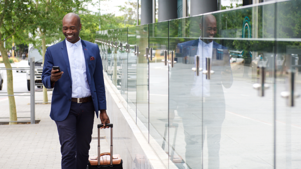 black man with suitcase on phone