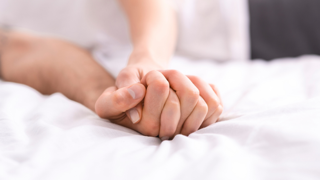 man and woman holding hands in bed