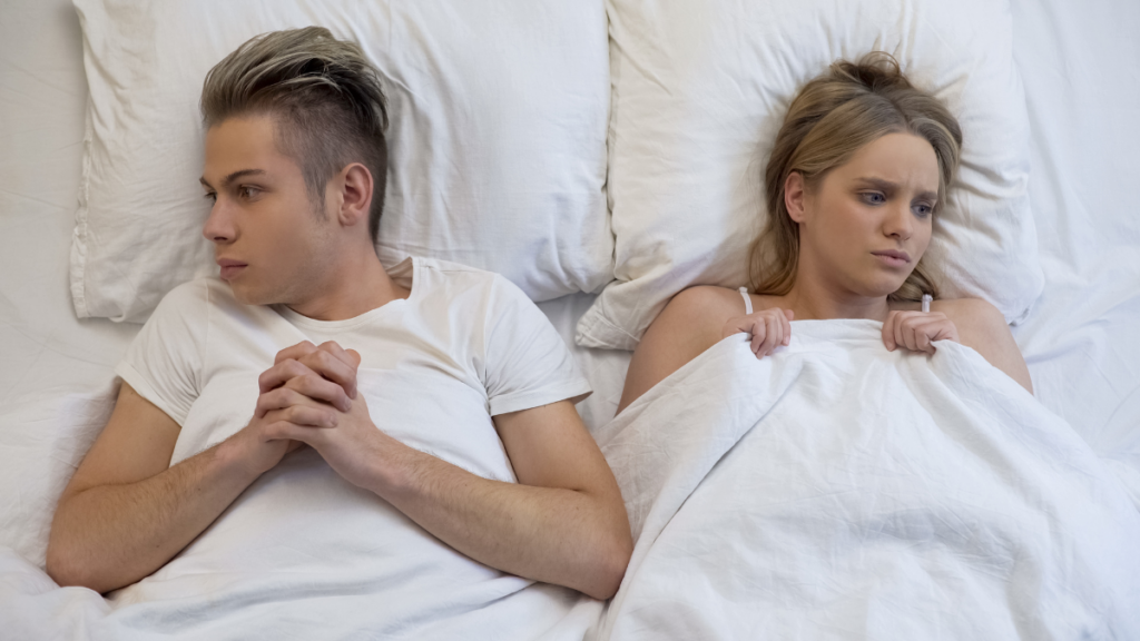 man and woman looking away from each other in bed