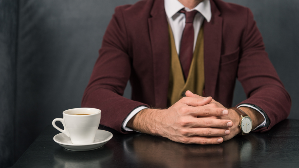 Man in suit sat with hands clasped together