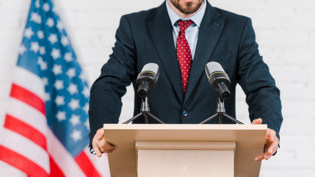 Man in suit standing behind microphone and a podium